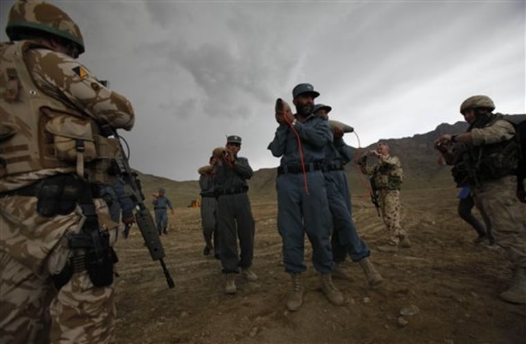 NATO soldiers take pictures as Afghan policemen carry shells to be used as explosives to destroy ammonium nitrate which was seized in Baricahb on the outskirts of Kabul, Afghanistan, on Wednesday.